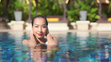 Close-up-of-a-beautiful-woman-pushing-back-her-wet-hair-after-a-dip-in-the-pool