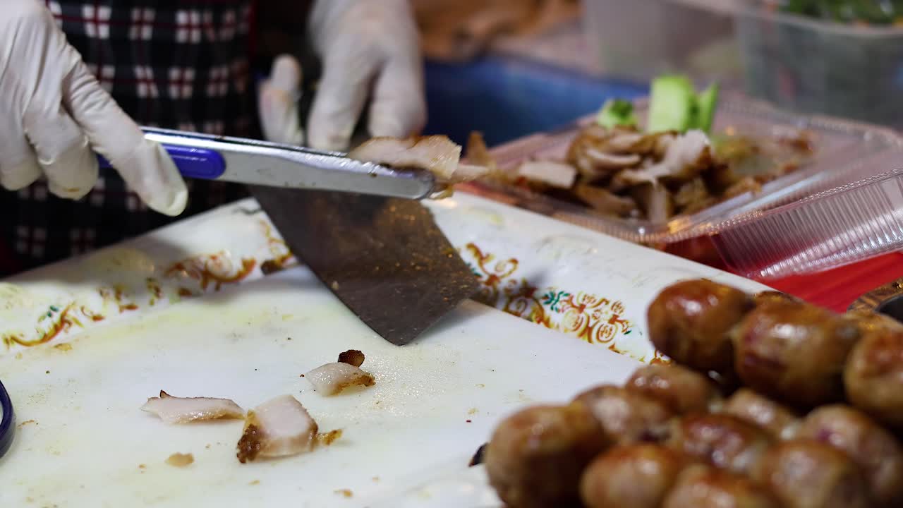 Chef slicing pork at a bustling food stall