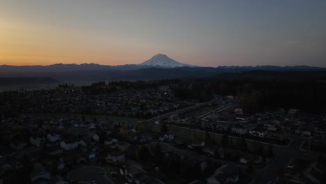 Aerial-pushing-towards-Mount-Rainier-at-sunrise-with-neighborhoods-underneath