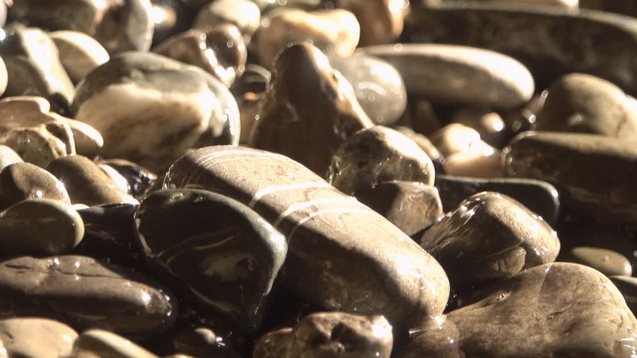 바다의 바위, 작은 돌의 질감, 바다의 파도에서 빛의 광선.