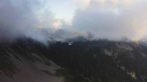 Sanfter-Lichtschein-Spiegelt-Sich-In-Den-Wolken-über-Alpinen-Wäldern-Und-Abfallenden-Felsigen-Hügeln