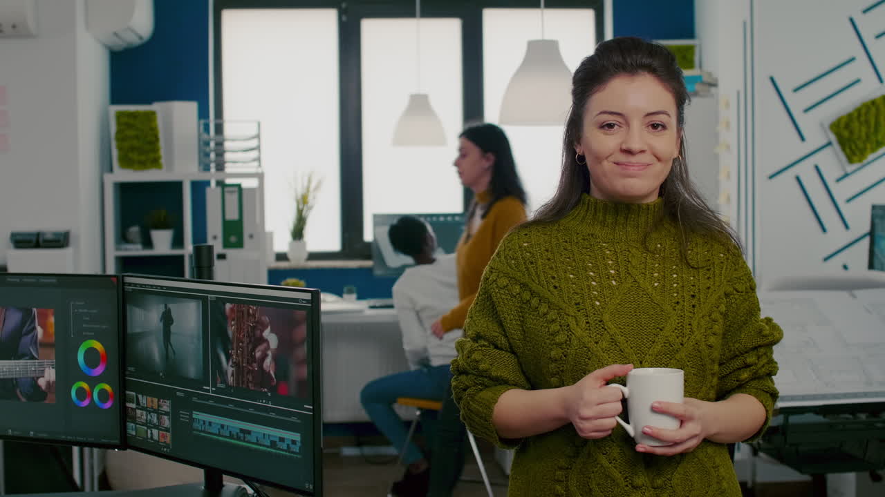 Portrait of creative designer smiling at camera holding a cup of coffee