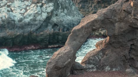 rock formation with hole along the coastal los gigantes promenade in the tenerife with ocean waves in the background