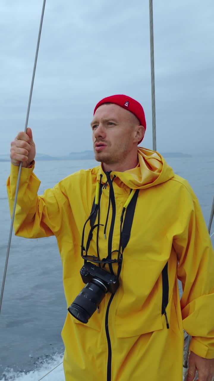 Hombre con impermeable amarillo navegando en el mar con una cámara
