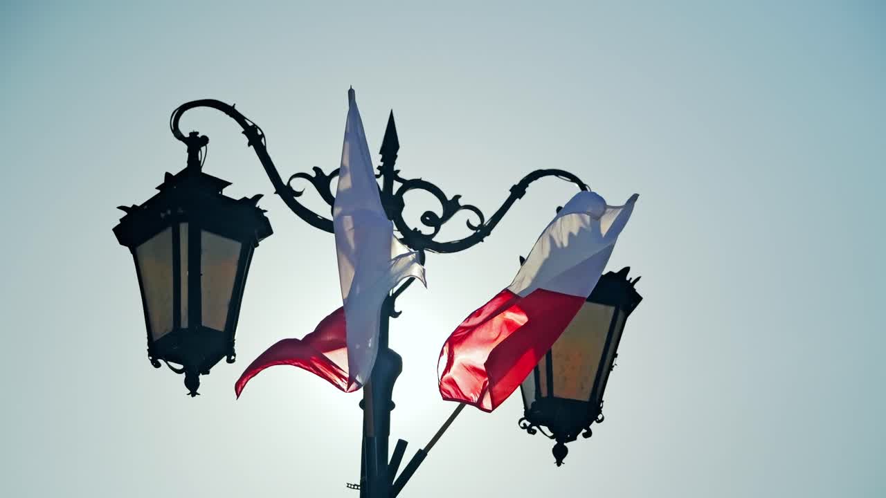 Polské národní vlajky vlající ve větru vedle pouličních lamp ve Varšavě, zpomalený záběr