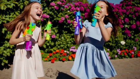 joyful girls playing with bubble guns and bubbles outdoors