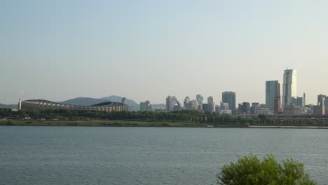 Jamsil-Arena-or-Jamsil-Sports-Complex,-Han-river-in-foreground-and-Hills-on-background-with-many-skyscrapers-and-High-buildings-in-sunset-light