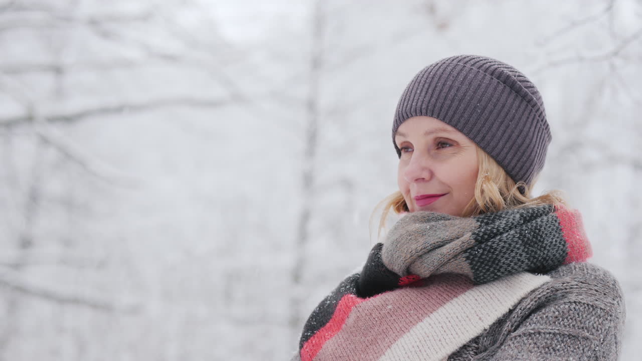 una mujer con un suéter cálido y una bufanda brillante se encuentra en un parque de nieve