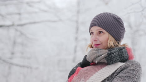 a woman in a warm sweater and a bright scarf stands in a snow park