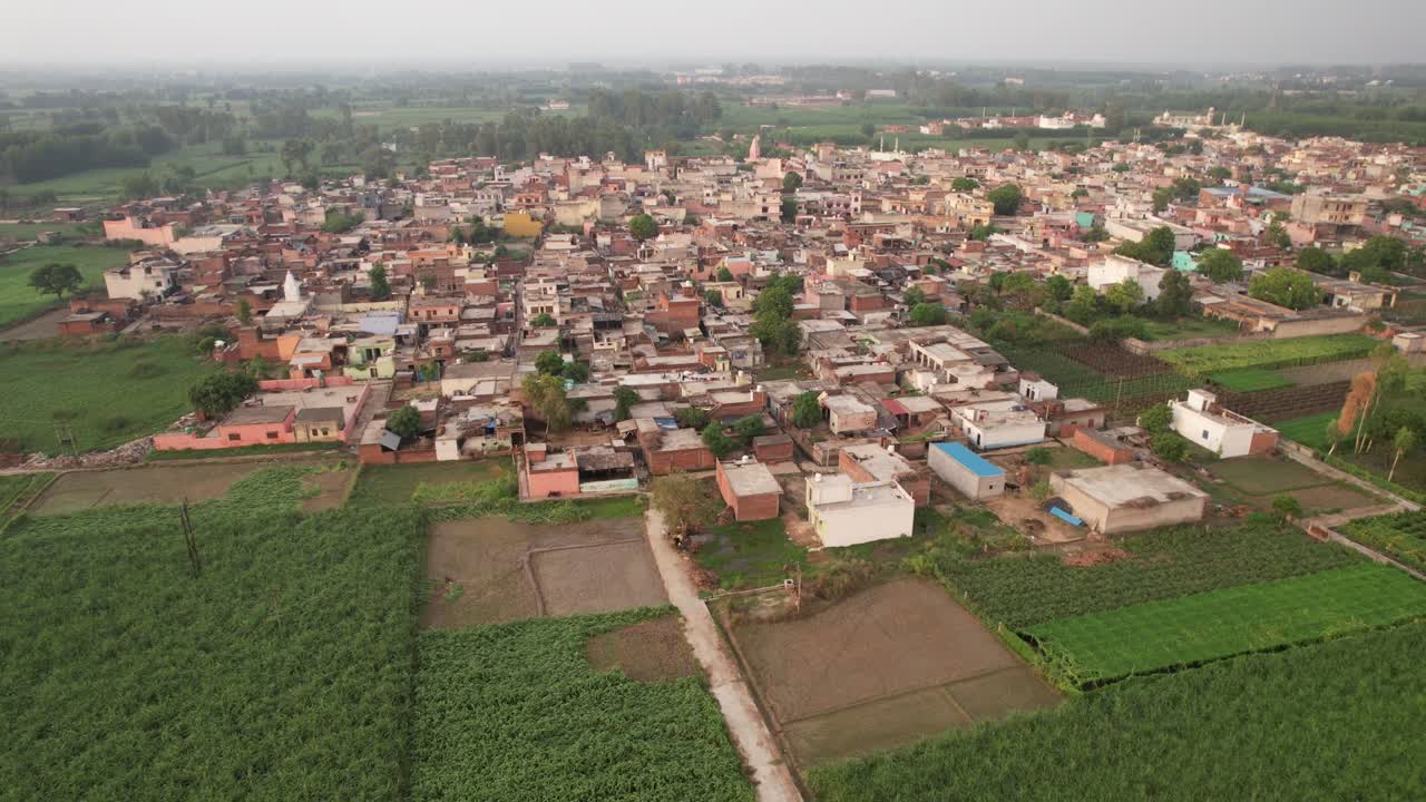 A beautiful golden hour shot of farms along with a small road leading towards a village which can be widely used for film purposes