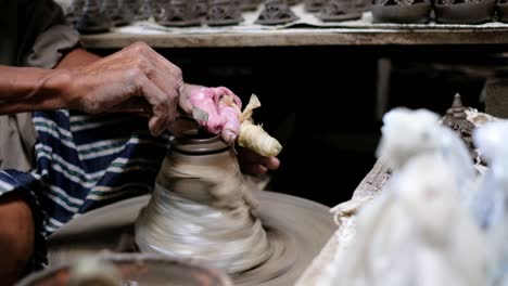 craftsman shaving the lid of clay pot