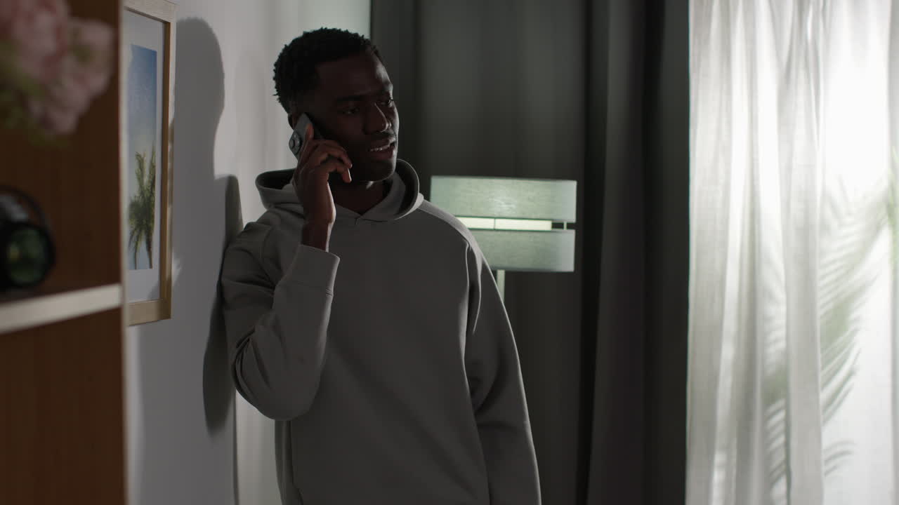 Young Man At Home Talking On Mobile Phone Reacting And Looking Upset After Getting Bad News