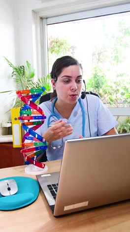 female doctor talking with patient through a video call with a laptop in the consultation.