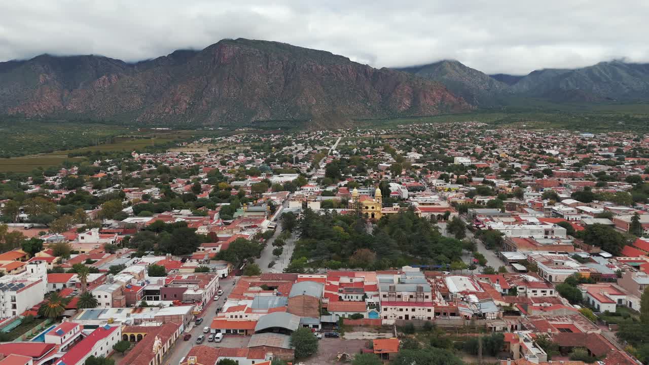 tomada aérea de drones de casas residenciales en cafayate, ciudad de salta, argentina, américa del sur, con colinas en el fondo.