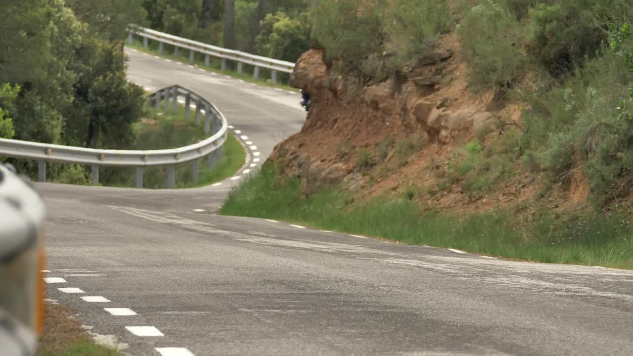 Motociclista solitario che guida su una strada forestale tortuosa e selvaggia