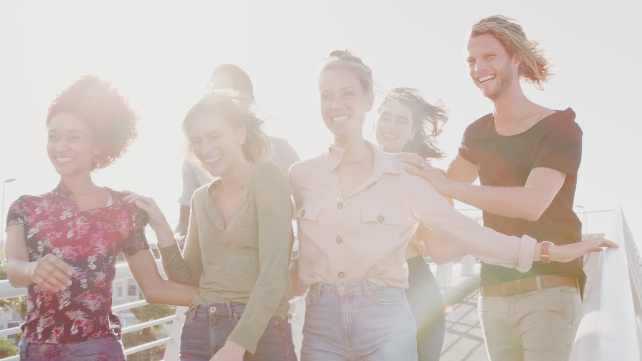 뜨거운 빛 에 대항 하여 다리 를 가로질러 함께 고 있는 젊은 친구 들 의 그룹