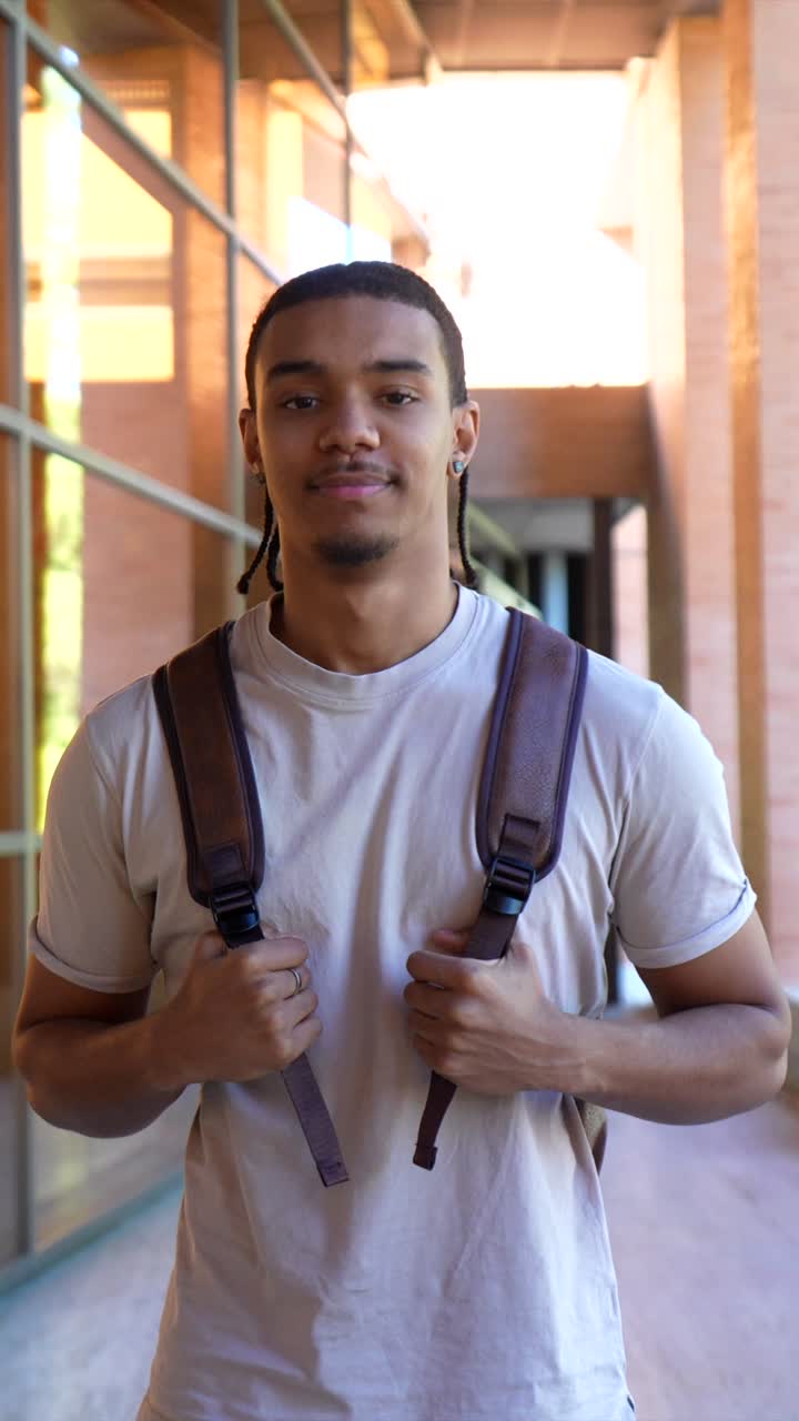 Jovem com Mochila em Pé e Sorrindo no Corredor Universitário