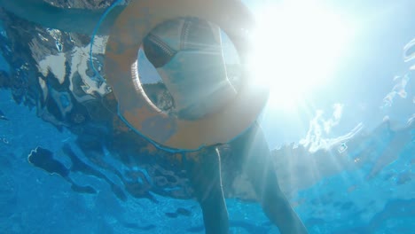 buena mujer relajándose en una piscina con anillo de seguridad inflable, cámara lenta, vista submarina