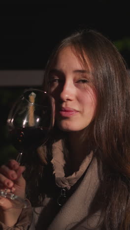 young wife drinks wine with husband during party. woman and man spend vacation together sitting in comfortable armchairs on terrace of glamping house