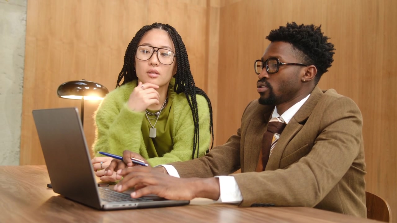 Black Businessman Using Laptop and Taking Notes during Discussion with Colleague