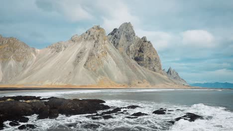 mountains and ocean waves on the coast of iceland beach