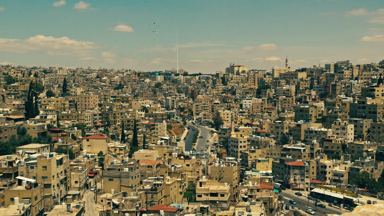 Paesaggio urbano cinematografico di Amman, Giordania, a mezzogiorno, che mostra le fitte proprietà di quartiere collinari, le strade tortuose e gli edifici illuminati dal sole sotto un cielo limpido