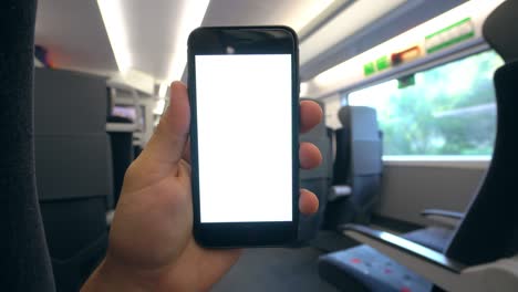 una mano sosteniendo un teléfono con una pantalla blanca en el tren