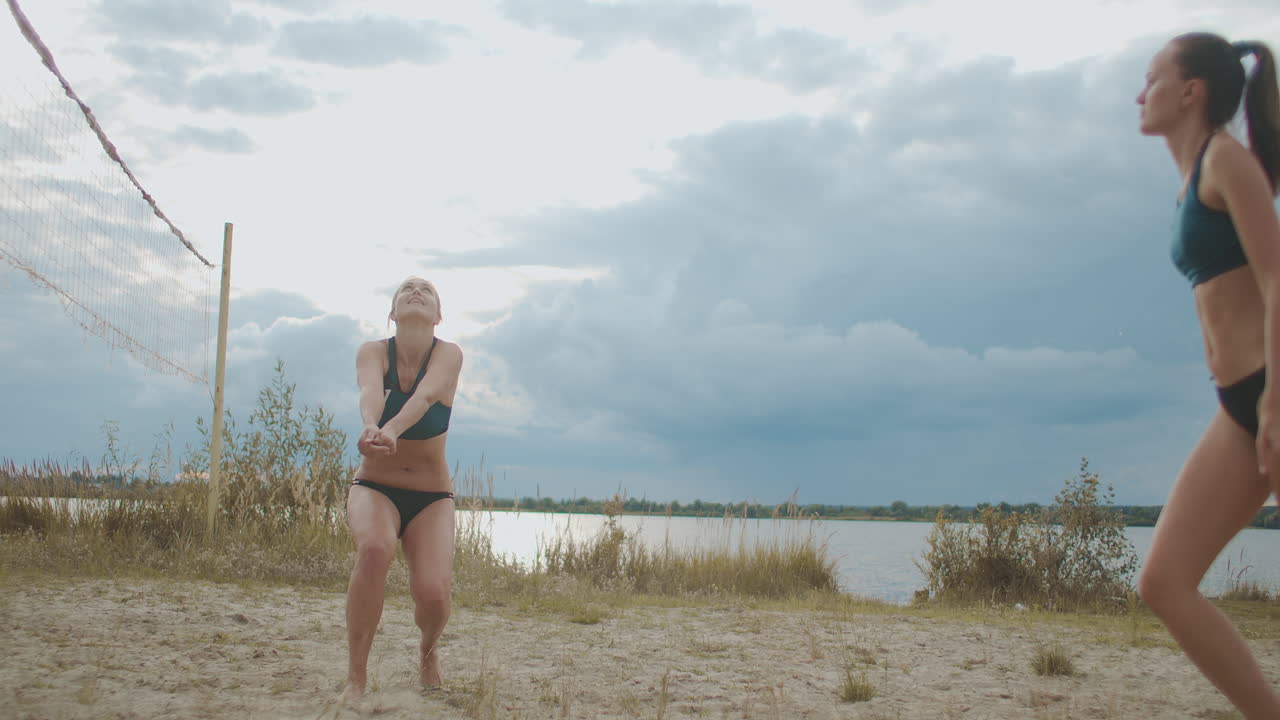 спортивные женщины играют в пляжный волейбол летом в замедленном движении против облачного неба в дневное время
