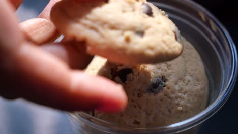 la mano recogiendo una galleta de chispas de chocolate de un recipiente