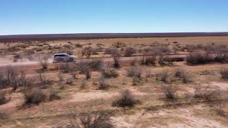 a 4x4 safari car drives over a long road in namibia