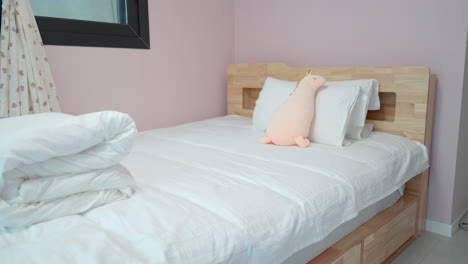 child bed with plush toy resting on white pillows in small, comfortable room