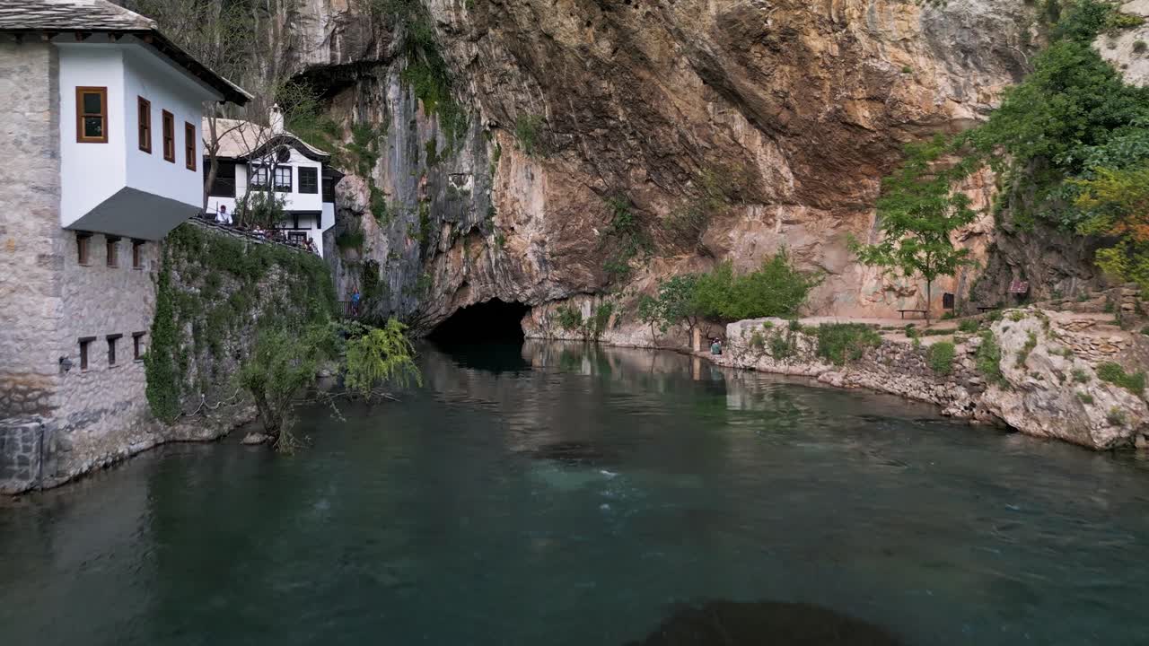 Drone shot along the river of Blagaj Monastary in Mostar, Bosnia. A river running under a mountain with the building built into the rocks