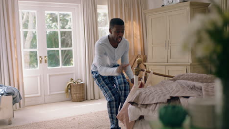 funny african american man dancing in bedroom having fun celebrating feeling positive enjoying successful lifestyle doing silly dance at home on weekend morning wearing pajamas