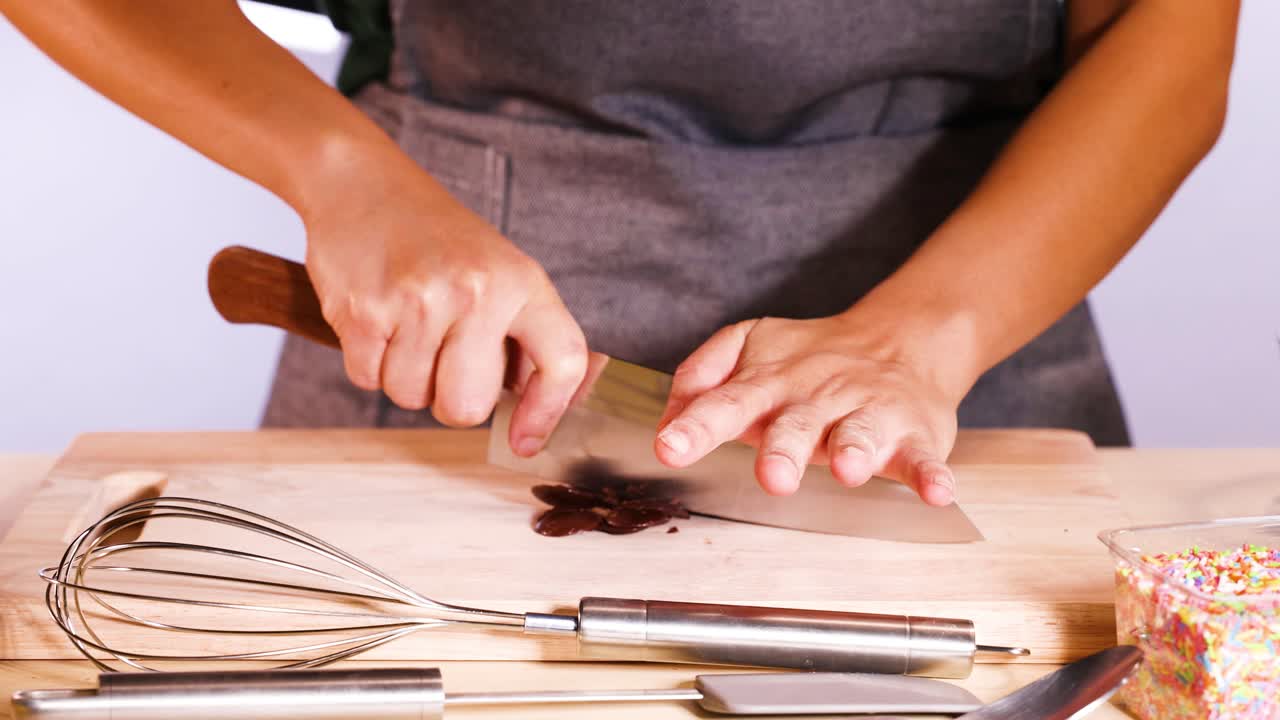 Person chopping chocolate discs with a knife