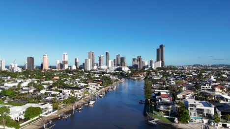 drone footage captures gold coast's skyline, river, and residential areas under clear blue skies, showcasing urban and natural harmony