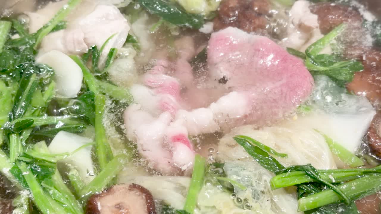 Marbled wagyu beef and fresh vegetables simmer in bubbling hotpot broth under bright, even lighting