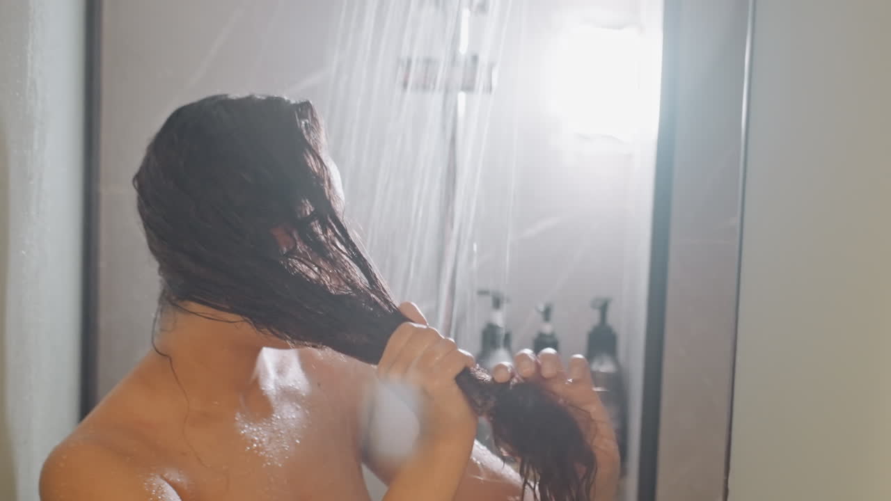 Huésped de hotel peinando su cabello largo y mojado. Visitante arreglando su cabello húmedo bajo una fuerte lluvia en una escena de baño. Persona gestionando su largo cabello húmedo en el baño del hotel durante una intensa tormenta diurna.