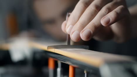 luthier comprueba el radio del fretboard de la guitarra eléctrica después de lijar, reparación de los instrumentos musicales en el taller de guitarra, 4k 60p 10 bits