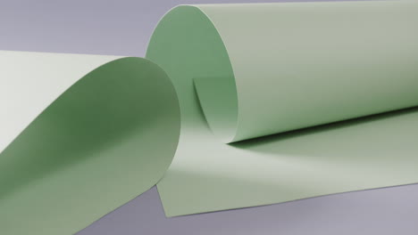 Close-up-of-two-pale-green-rolled-pieces-of-paper-on-blue-background-with-copy-space-in-slow-motion