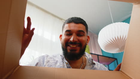 hombre indio feliz comprador desempaquetando caja de cartón entrega paquete compras en línea compra en casa