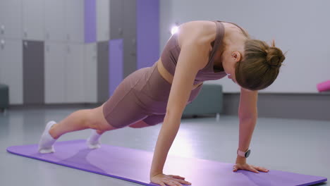 athlete engages in deep stretch on purple mat in modern gym setting, with soft lighting reflecting off background, fitness flexibility and focus emphasized in this workout posture