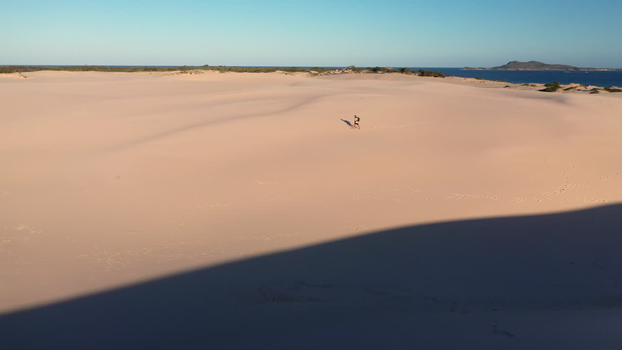 excursionista caminando solo en las dunas de arena de punto oscuro en hawks nest, nueva gales del sur, australia