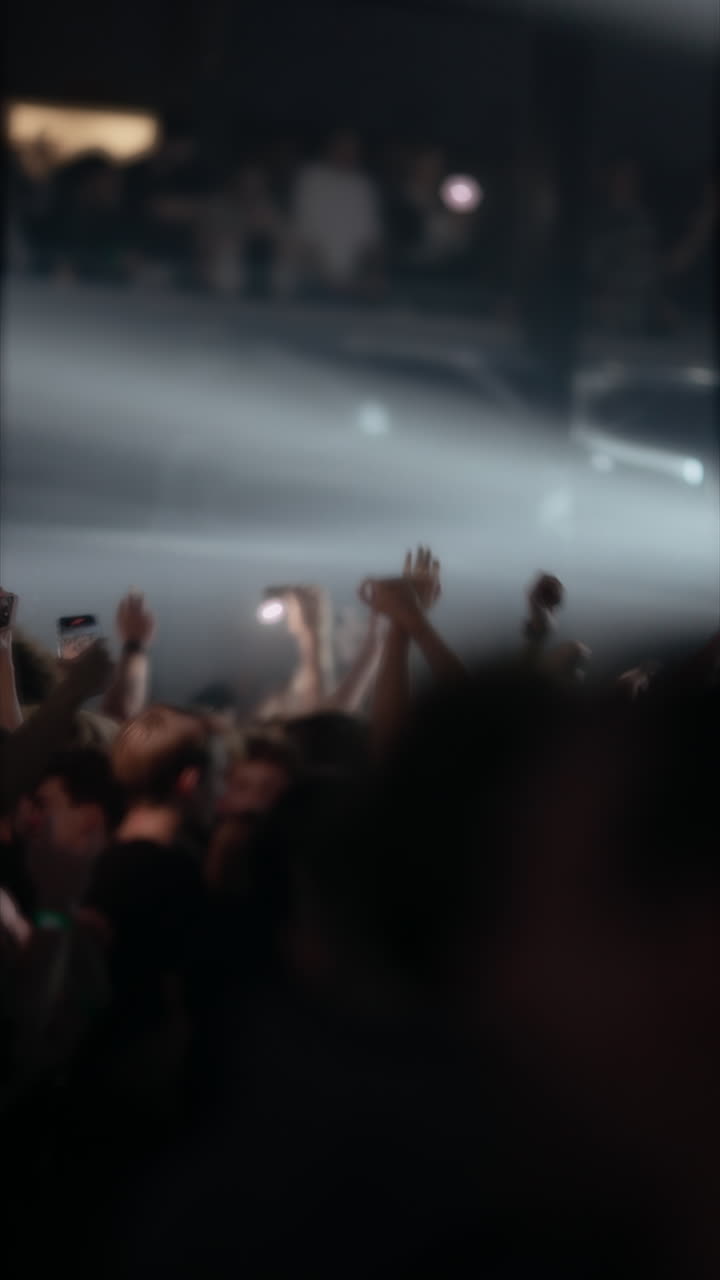 Visuale sfocata di una folla piena di energia che alza le mani a un concerto