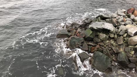 Water-hits-bedrock-on-shoreline,-slow-motion-long-shot