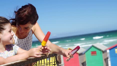 mother and daughter having ice cream at beach