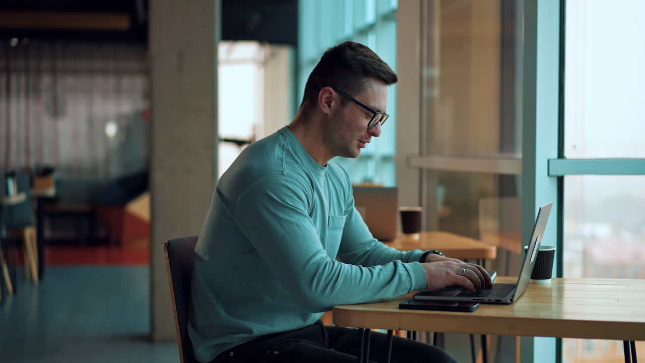 hombre trabajando en una computadora portátil en un café