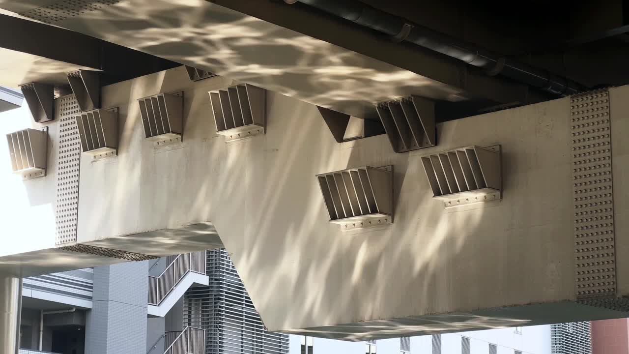 Udsigt under broen af airconditionanlæg der kaster skygger, urban infrastruktur.