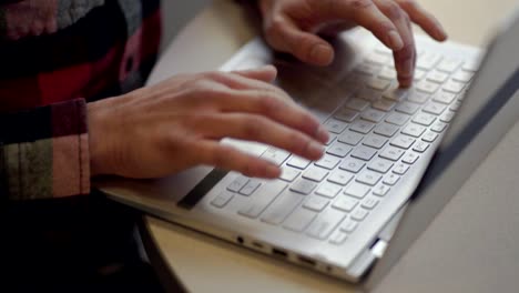 A-young-man-typing-on-his-keyboard-laptop,-online---Close-up-pan-up-shot