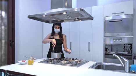 young woman cooking food for delivery in protective mask