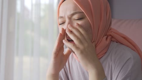 woman in headscarf screaming at home.